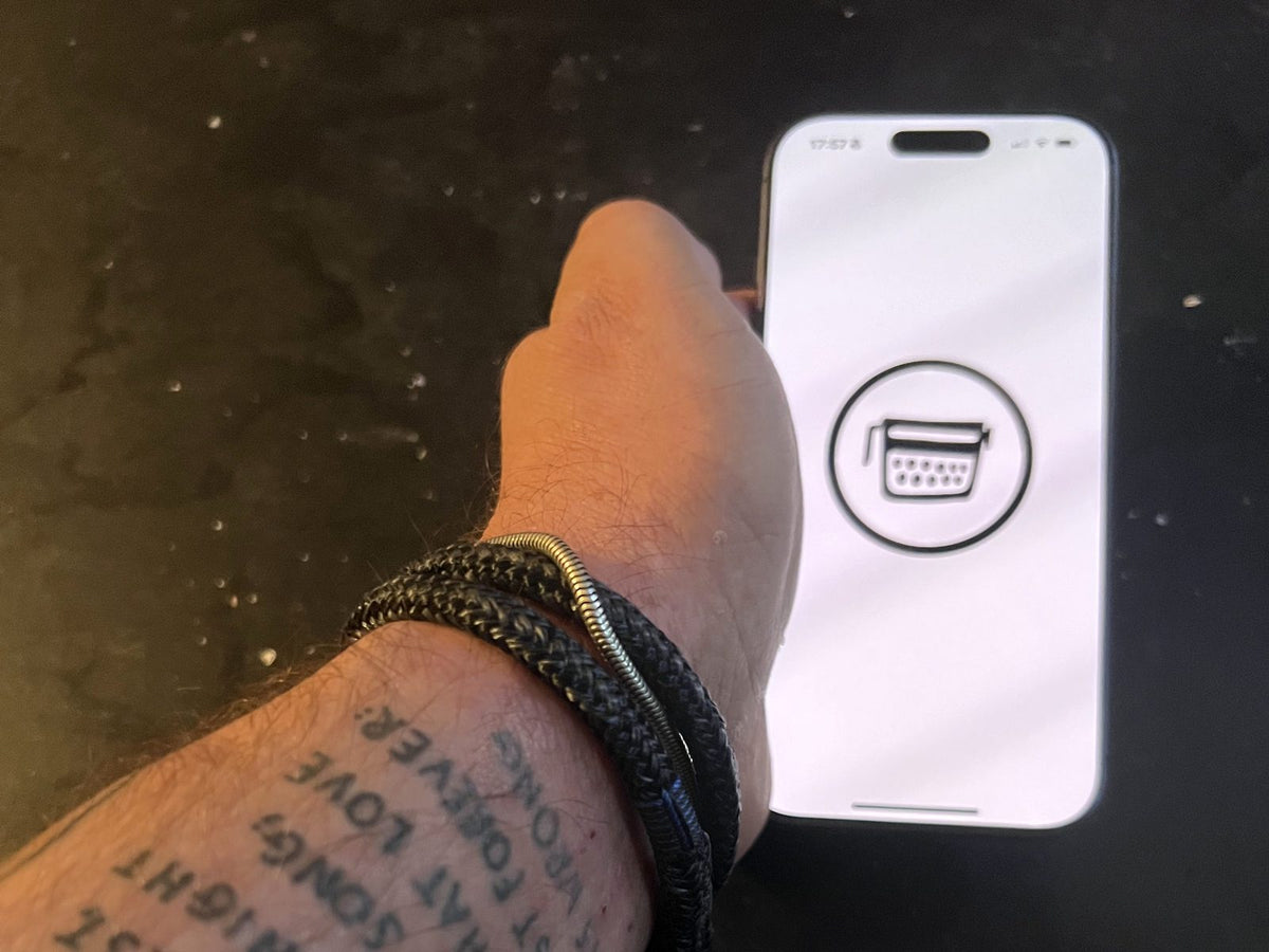 Hand mit iPhone, auf dem Display das Schreibmaschinen-Logo der App »poetisiert euch!«